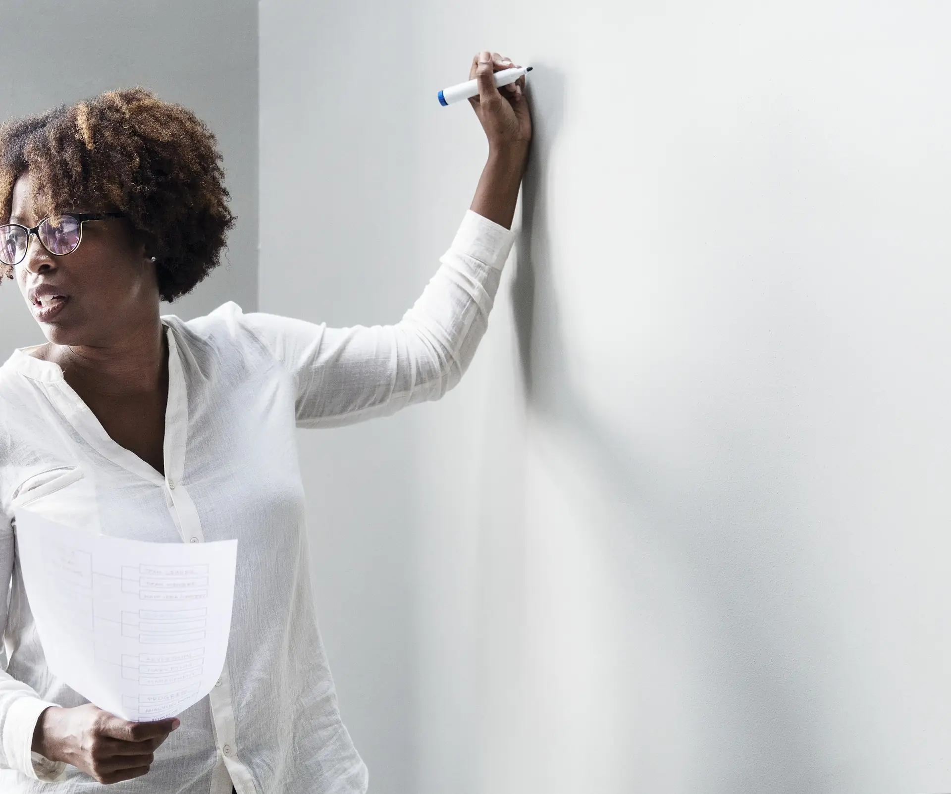 Bookkeeper writing figures on a whiteboard with notes in hand
