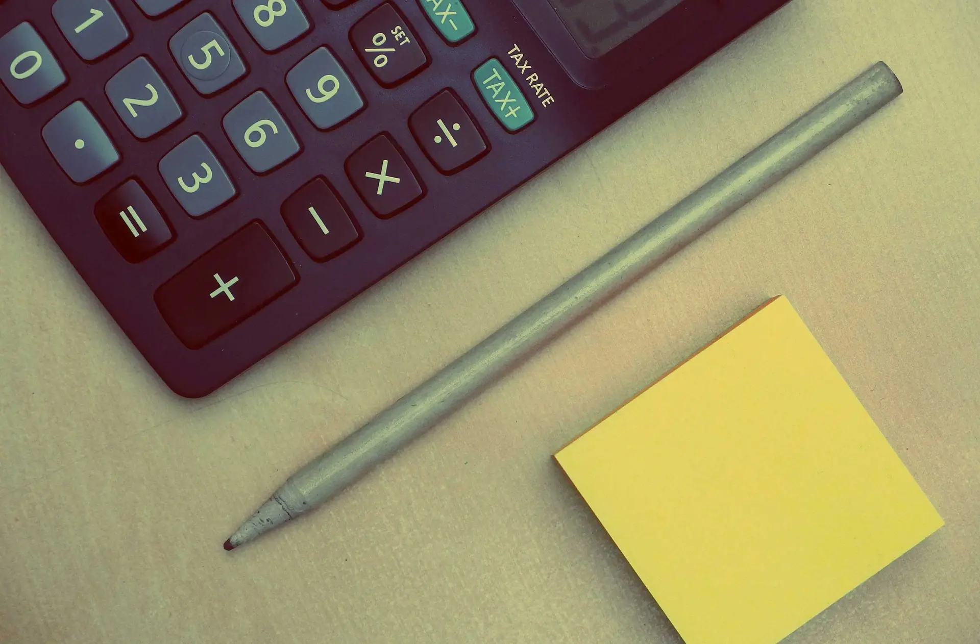Calculator, pencil and a sticky note on a desk