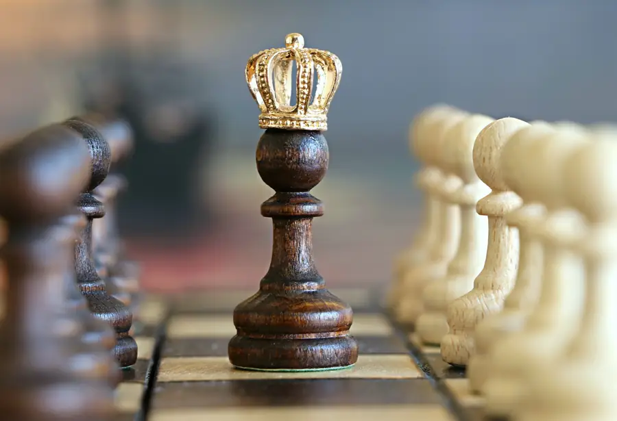 Chess king standing in front of a line of pawns