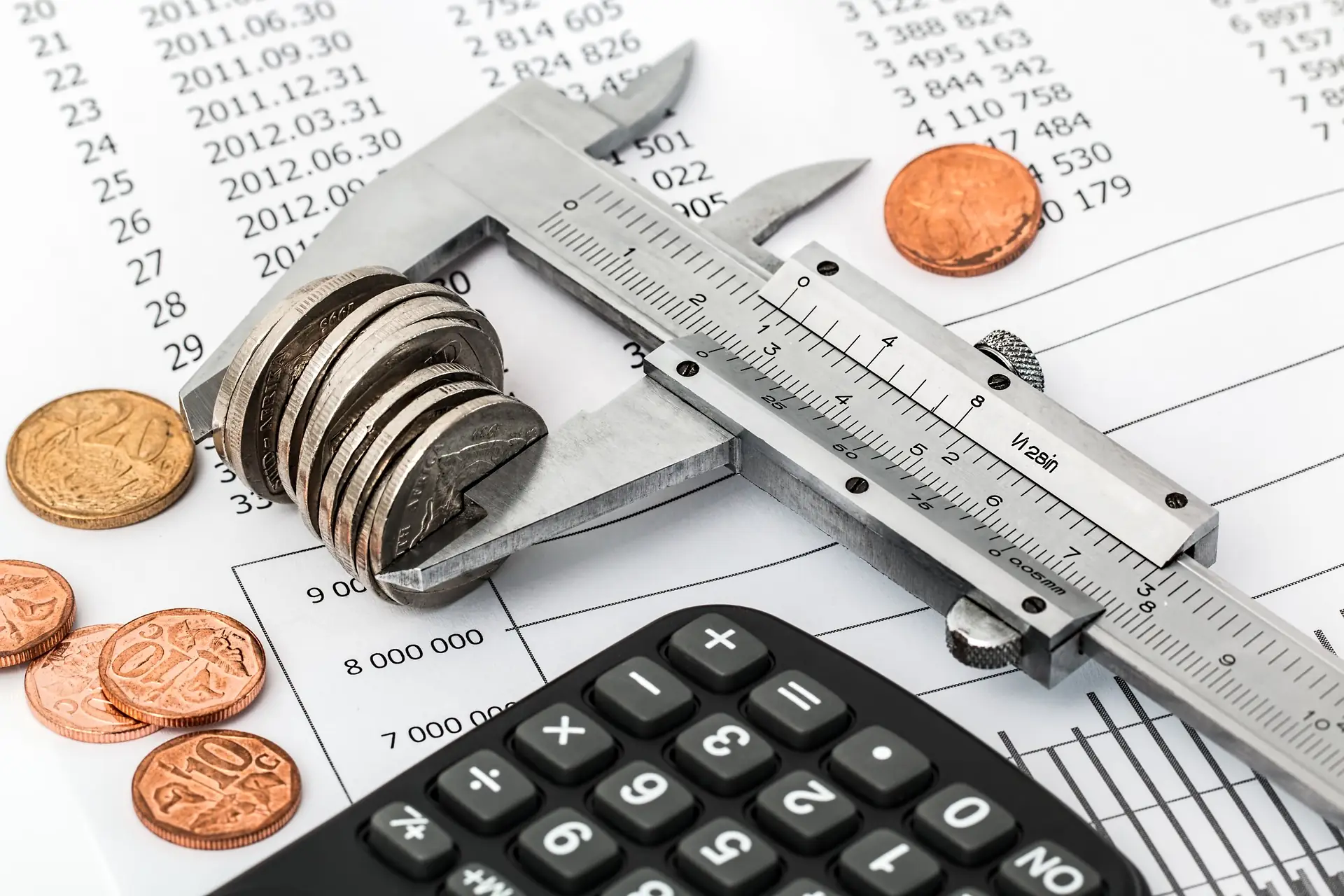Coins measured with a caliper on top of a calculator and printed figures